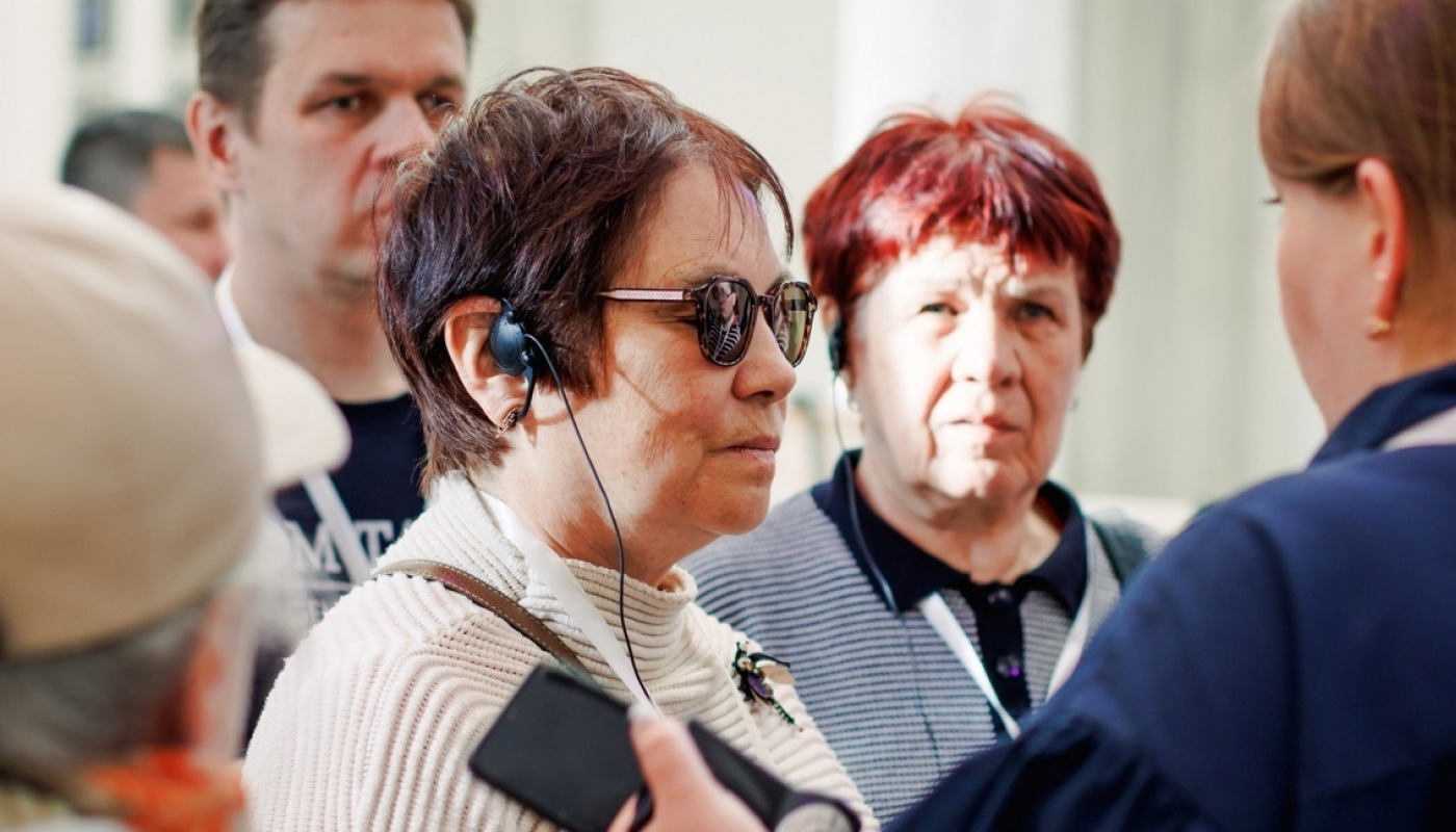Пожилая женщина с оборудованием для слабослышащих и слабовидящих